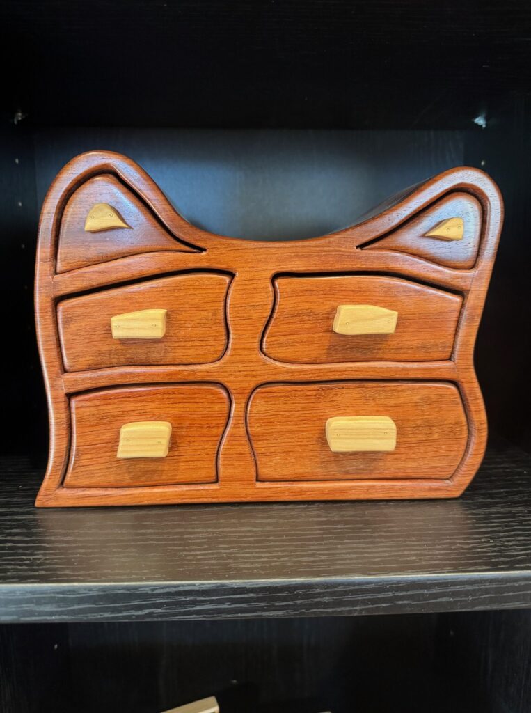 Handcrafted wooden jewelry box with curved drawers displayed in the House of Clay gallery.