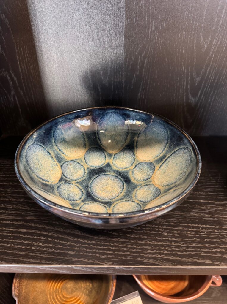 Handmade ceramic bowl with textured circular pattern and blue glaze displayed in the House of Clay gallery.