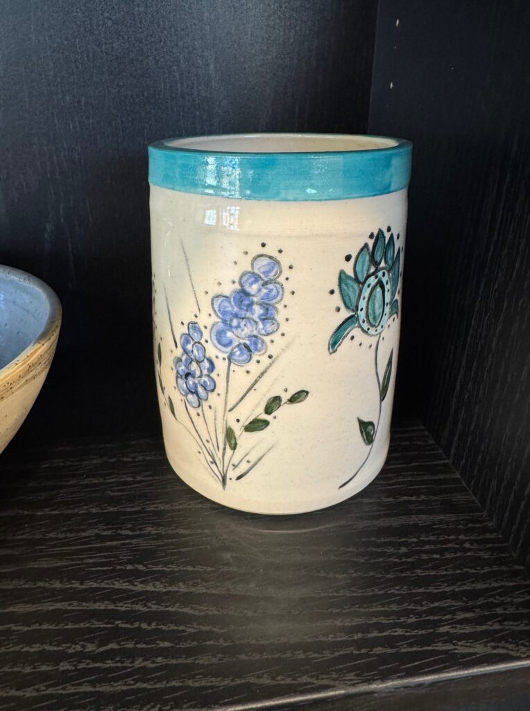Handmade ceramic vase with blue floral designs and turquoise rim displayed in the House of Clay gallery.