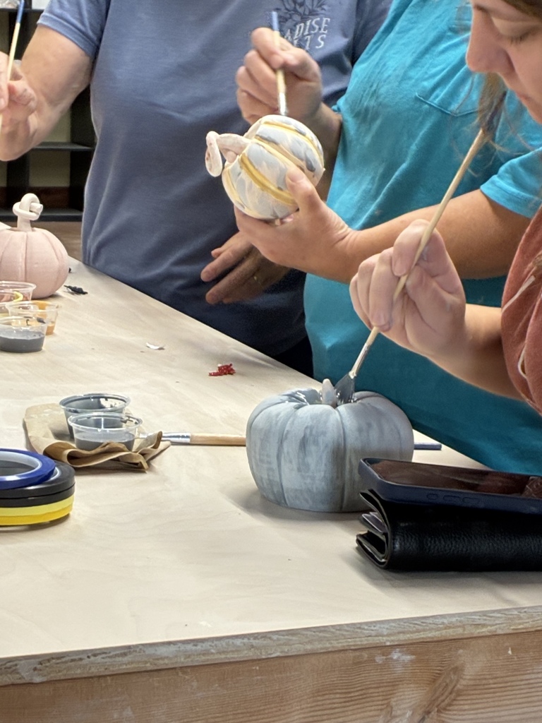 Participants glazing ceramic pumpkins during Raku Day at House of Clay in Overland Park